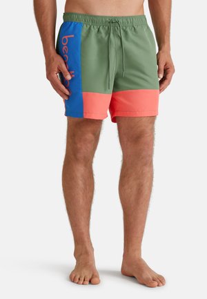 Costumi da bagno colorati con corpo verde, pannello laterale blu con testo rosso e fondo corallo. Realizzati in materiale leggero.
