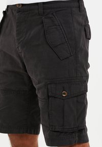 Shorts cargo noirs en tissu durable, dotés de plusieurs poches, d'une fermeture à bouton et d'une coupe décontractée avec des ourlets retroussés.
