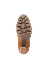 Zapato de ante marrón con una suela de goma texturizada que presenta patrones cruzados, puntera redondeada y un tacón bajo. La suela exterior está diseñada para ofrecer agarre.