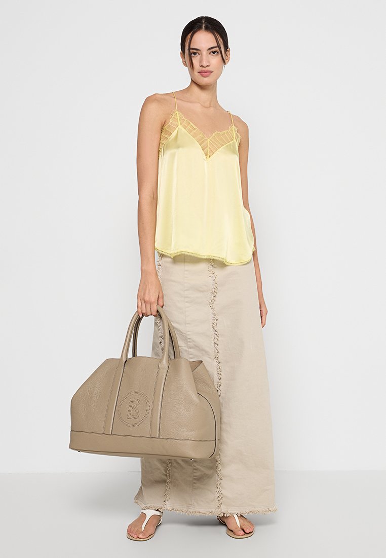 Geel satijnen camisole met kantaccenten, gecombineerd met een beige leren tote bag met structuur en een beige rok met gestikte details.