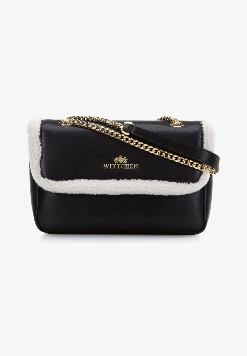 Zwarte leren handtas met een witte schapenfellen rand, gouden hardware en een schouderband van ketting. De voorkant heeft een in goud verdiept logo.