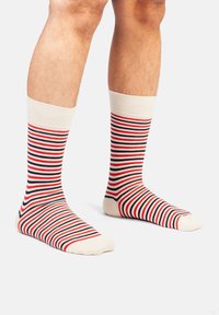 Baumwollsocken mit horizontalen Streifen in Rot, Marineblau und Creme. Gerippter Bund, knöchellange Ausführung und glatte Textur auf dem Fuß.