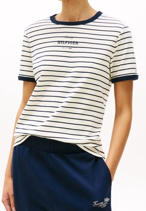 Koszulka bawełniana w paski w kolorze kremowym i granatowym, okrągły dekolt z kontrastowym wykończeniem, z nadrukiem logo. W połączeniu z granatowymi spodniami elastycznymi w pasie.