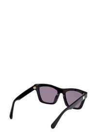 Černé obdélníkové sluneční brýle s tlustými rámy a tmavými zabarvenými skly, zobrazené ze zadního úhlu na bílém pozadí.