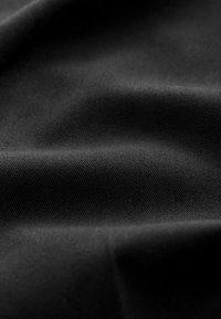 Svart textil med en slät, vävd struktur, med subtila räfflor och veck som fångar ljuset i en matt yta.