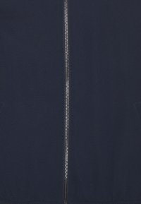 Námořnicky modrá bomber bunda s předním zipem, vyrobená z texturované látky, s dvěma bočními kapsami a žebrovanými manžetami.