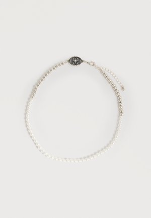 Halskæde med vekslende hvide perler og sølvperler, med en sort oval lås med et hvidt kompasdesign og en justerbar kæde.