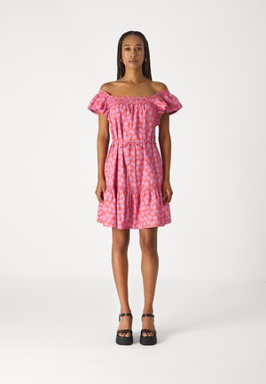 Pink off-shoulder dress featuring a floral pattern, elastic smocked bodice, tiered ruffle hem, and short sleeves, paired with black platform shoes.