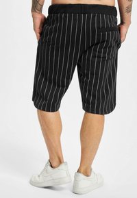 Shorts negri cu dungi, din bumbac, cu un croi relaxat, talie elastică și un singur buzunar la spate. Potriviți cu adidași albi.