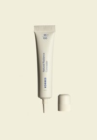 Weißer Tubus des Korres Natural Radiance Concealers mit blauer Schrift, ausgestattet mit einer spitzen Düse und einem abnehmbaren Deckel.