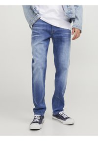 Blå denimjeans med en blekt finish, rak passform, kontrastsömmar och femficksdesign, kombinerade med marinblå sneakers.