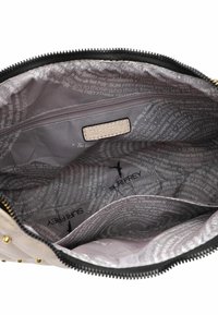 Indvendig af beige taske med lynlåslomme, stofforing prydet med "SURI FREY" tekst og fuglelogo.