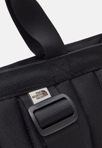 Czarna torba tote z nylonu, z plecionym paskiem, plastikową klamrą oraz małą metką z logo "The North Face".