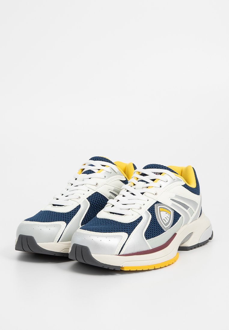 Sneakers sportive blu navy e bianche con tomaia in rete, suola in gomma, dettagli gialli e un logo argento di lato. Collo e linguetta imbottiti.