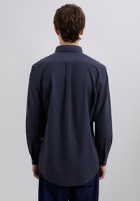 Camisa de manga larga azul oscuro con un patrón de cuadros, cuello abotonado y puños con un solo botón. Textura suave, dobladillo recto.