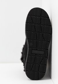 Semelle de botte d'hiver noire avec un motif de bande de roulement profond et le logo "Tom Tailor" sur fond blanc.