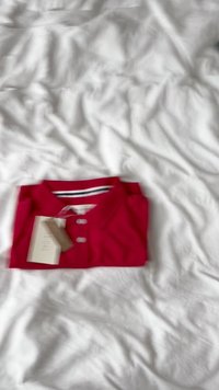 Maglietta polo rossa in cotone con tre bottoni, colletto e dettagli a righe all'interno. Etichetta attaccata alla maglietta.