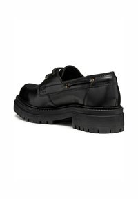 Chaussure en cuir noir avec un bout arrondi, des détails de couture et une semelle en caoutchouc épaisse et texturée. Comprend des œillets en métal pour les lacets.
