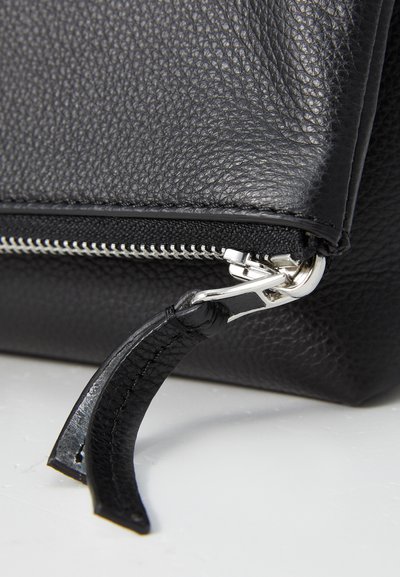 Geantă neagră din piele cu o suprafață texturată, având un fermoar argintiu și un tab de tragere din piele, evidențiind un design modern minimalist.