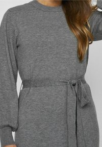 Abito maglione grigio a maglia con maniche lunghe, scollatura rotonda, cintura annodata in vita e polsini a coste, caratterizzato da una texture morbida e un design semplice.