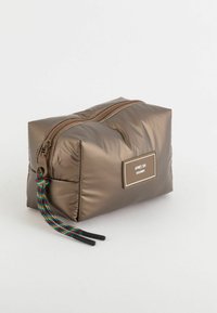 Brun polstret kosmetikpose med lynlås, der har en dekorativ trækflap og et mærke, der står "APRES SKI DOLOMITI."