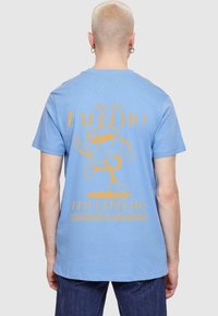 Light blue cotton t-shirt featuring a yellow graphic of a cartoon character with the text "NOE ESPRESSO LESS EPRESSO" on the back.