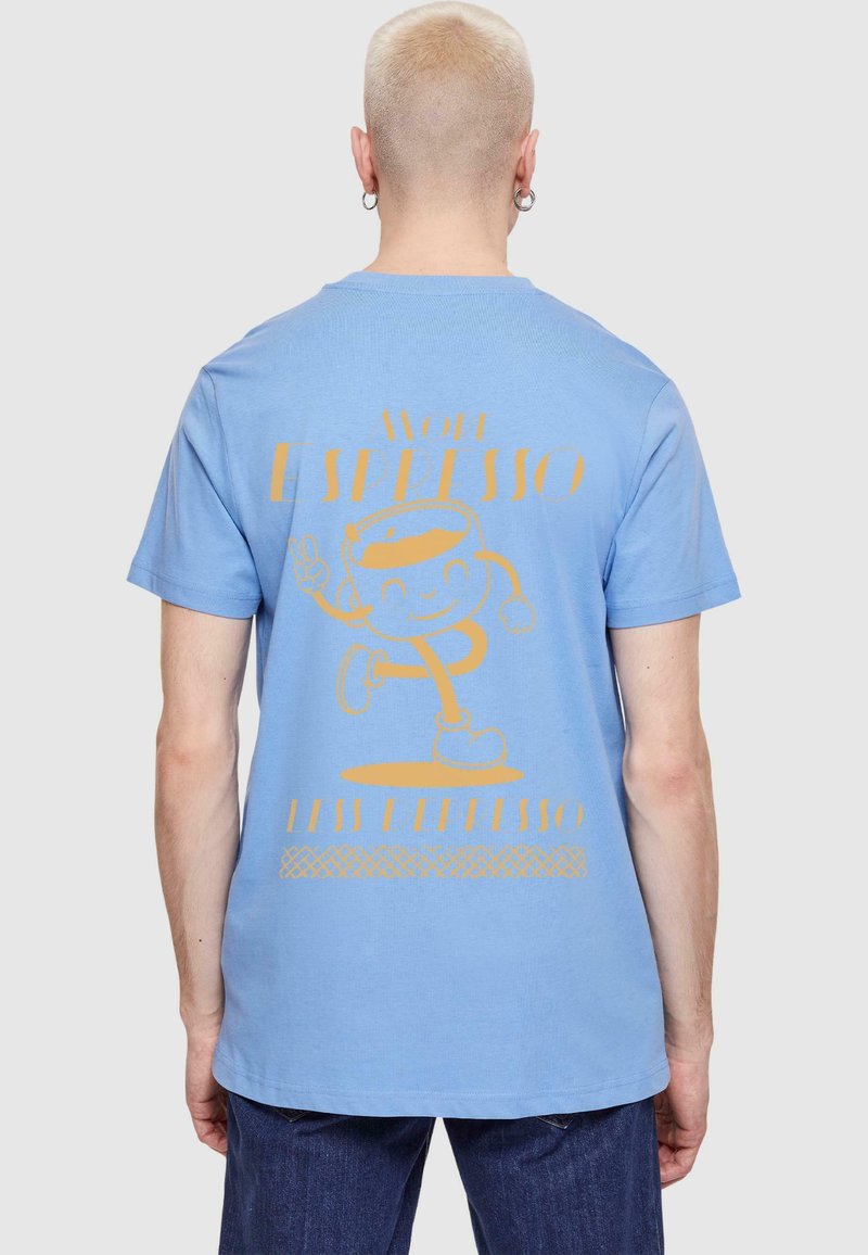 Light blue cotton t-shirt featuring a yellow graphic of a cartoon character with the text "NOE ESPRESSO LESS EPRESSO" on the back.