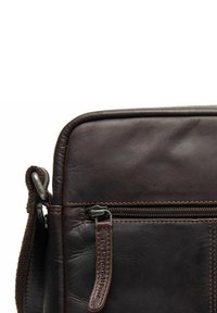 Borsa in pelle marrone con una texture liscia, tasca con zip e dettagli cuciti. Presenta una tracolla removibile e bordi arrotondati.