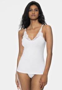 Valkoinen puuvillatoppi, jossa on pitsireunus kaula-aukossa ja säädettävät olkaimet. Topissa on slim fit -malli ja sileä pinta.