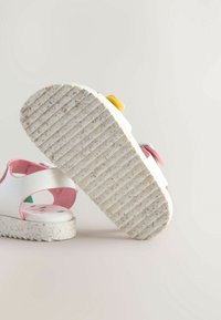 Witte sandalen met roze accenten, gestructureerde loopzool en een gespikkelde zool. Voorzien van een verstelbare band en kleurrijke versieringen bovenop.
