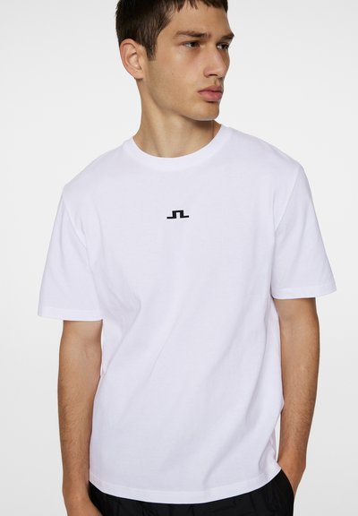 Hvit bomulls t-skjorte med et sentrert svart logo på brystet. Korte ermer og klassisk rund hals-design. Lett og glatt tekstur.