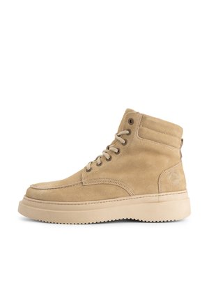Beige suède enkellaarsjes met een ronde neus, contrasterende stiksels en een rubberen zool. Inclusief veterogen en padding rond de enkel.