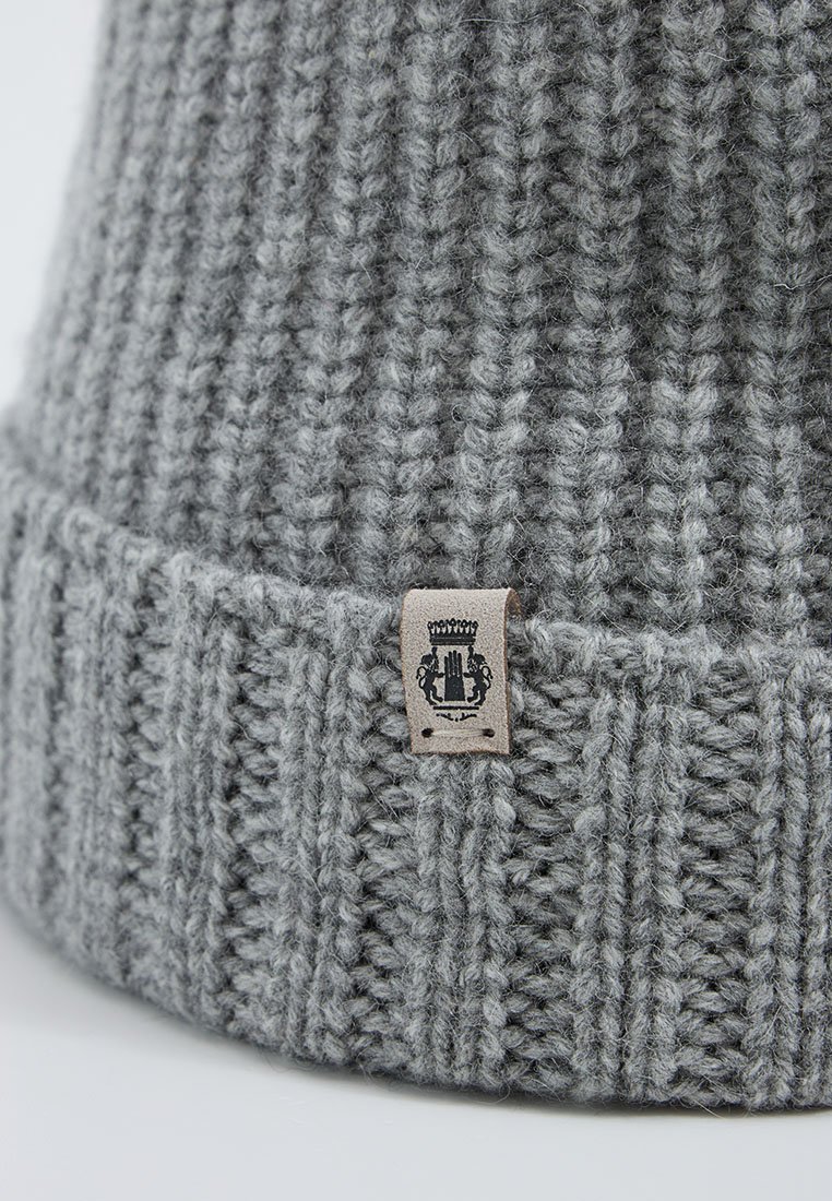 Szara dzianinowa czapka z prążkowanym wzorem i zawiniętym mankietem. Posiada małą skórzaną metkę z logo herbu.