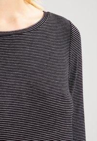 Schwarz-weißer gestreifter Langarmshirt mit rundem Halsausschnitt. Der Stoff wirkt weich mit einer glatten Textur und weist dünne horizontale Linien auf.
