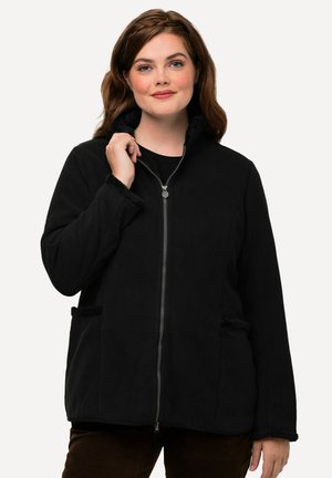 Veste zippée noire avec un col haut, des finitions texturées et des poches latérales. Fabriquée en matériau doux, elle présente une coupe décontractée et des manches longues.