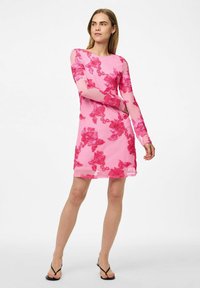 Vestido corto rosa con mangas largas y transparentes, que presenta un patrón floral en rosa más oscuro, con un corte recto y un dobladillo a la altura de la rodilla.