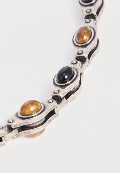 Bracelet en argent avec pierres ovales alternées en ambre et pierres noires polies, serties dans des montures métalliques décoratives reliées.