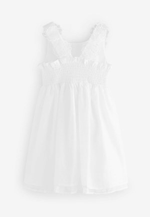 Balta suknelė su gėlių akcentais ant dirželių, smulkinta krūtinė ir laisvas sijonas. Pagaminta iš lengvos medžiagos su minkšta tekstūra.