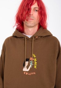 Felpa marrone con cappuccio a stringa, caratterizzata da una grafica colorata di una persona che tiene dei fiori e il testo "YOU AGAIN" e "VOLCOM."