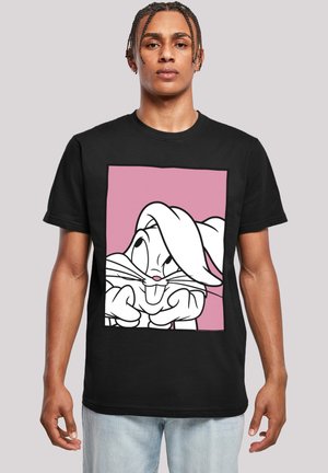 Svart T-skjorte med grafikk av en tegneseriefigur med overdrevent trekk på en rosa bakgrunn. Korte ermer, laget av bomull.