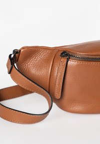 Bruine leren crossbody tas met een gestructureerd oppervlak, een zwarte rits en een verstelbare strip met een bijpassend leren accent.