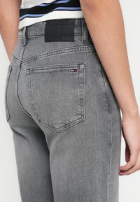 Hallid teksariidest püksid, mis on kehakuju järgivad. Omadusteks on must nahast vööümbris brändi logoga ja väike kolmemõõtmeline logo taga taskul.