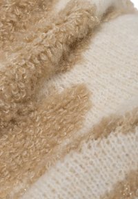 Strickstoff mit unterschiedlichen Texturen in Beige und Creme, der flauschige und glatte Abschnitte mit dezenten Glitzereffekten zeigt.
