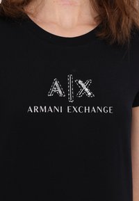 Tricou negru din bumbac cu logo-ul "A|X ARMANI EXCHANGE" decorat cu accente de strasuri, guler rotund și mâneci scurte.