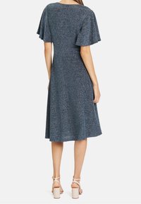 Modré texturované šaty s krátkými volánkovými rukávy, kulatým výstřihem a rozšířenou sukní, doplněné masivními tělovými lodičkami.