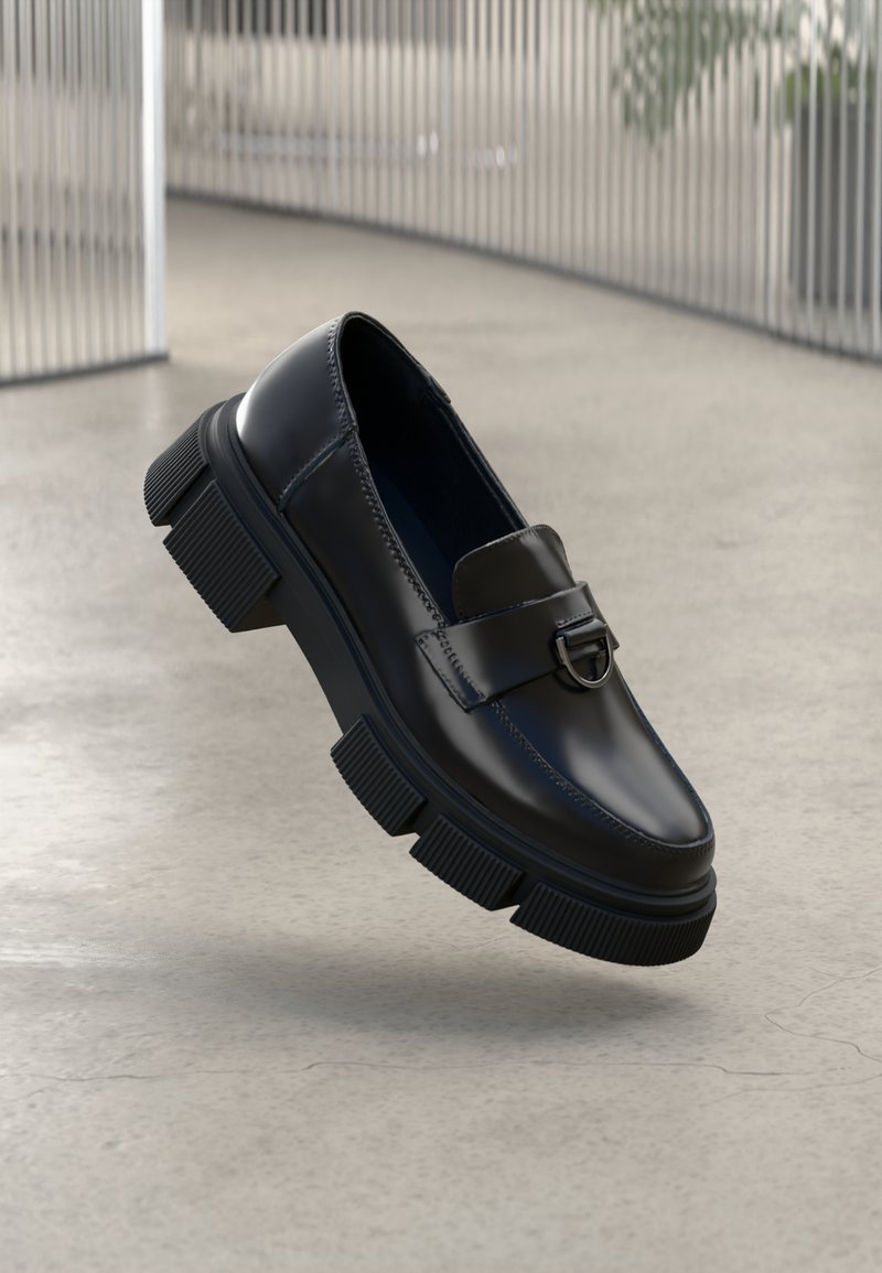 Black leather loafers with a chunky rubber sole and pronounced tread. Features a front strap with a circular metal accent.