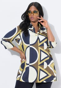 Tunic colorato e con motivi geometrici, caratterizzato da cerchi e triangoli in crema, blu navy, oliva e marrone. Tessuto leggero con colletto e maniche a tre quarti.