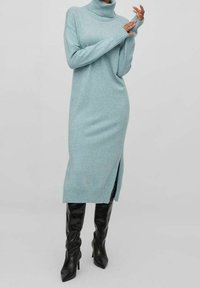 Ljusblå polotröja klänning med sidoklyfta, ribbade muddar och fåll. Bärs med knähöga svarta läderstövlar.