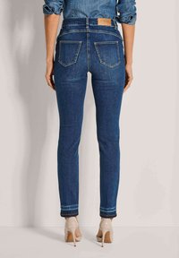 Donkerblauwe denim jeans met een slim fit, met achterzakken en een label op de tailleband. Accenten zijn onder andere een manchetafwerking met contrasterende stiksels.