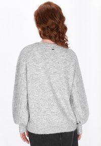 Maglione grigio lavorato a maglia con una vestibilità rilassata, maniche a costine e scollatura rotonda. Texture morbida e dettagli di cucitura a vista sul retro.